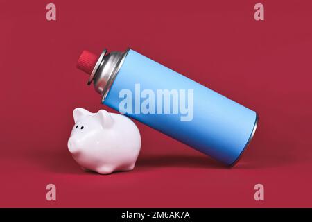 Gas cartridge bottle with piggy bank on red background. Concept for saving gas. Stock Photo