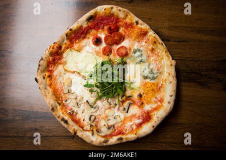 Four Seasons Pizza. Neapolitan pizza with tomato sauce, cheese, ham, mushrooms and vegetables. Authentic Italian recipe. Stock Photo