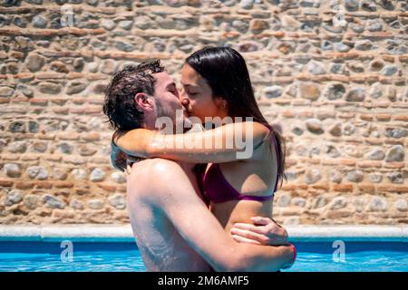 Young couple in love playing and kissing in the pool Stock Photo