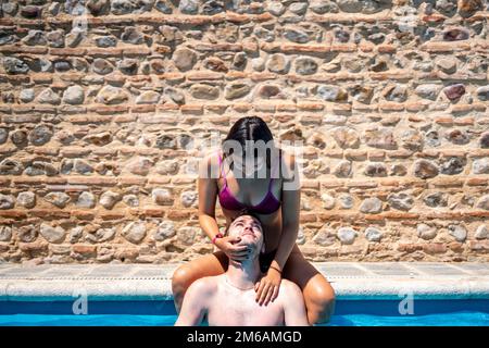 Young couple in love playing and kissing in the pool Stock Photo