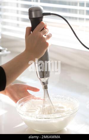 Electric mixer whisking egg whites in a glass bowl Stock Photo - Alamy