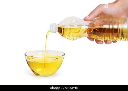 Sunflower oil pouring from bottle in a glass bowl. Isolated on white background. Stock Photo