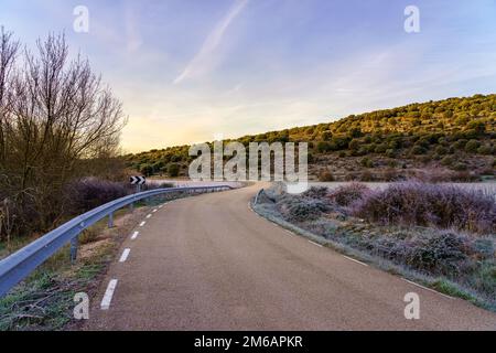 Icy road at sunset on a cold winter day in the frozen countryside. Stock Photo