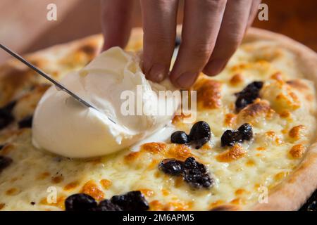 Bufala and black olives Pizza. Neapolitan pizza made with tomato sauce, mozzarella cheese and some vegetables. Italian recipe. Stock Photo