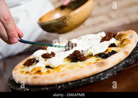 Bufala and black olives Pizza. Neapolitan pizza made with tomato sauce, mozzarella cheese and some vegetables. Italian recipe. Stock Photo