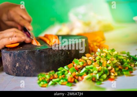 Hands cutting carrot pieces on a homemade chopper. Close up of hands chopping carrots in a wooden chopper. Concept of hands cutting vegetables in a Stock Photo