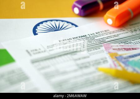 KYIV, UKRAINE - MAY 4, 2022 Indian income tax return blank form with pen and indian rupees bills on indian country flag close up. Annual tax report concept Stock Photo