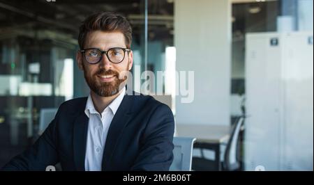 Successful person concept. Portrait of confident bearded businessman standing in office and posing at camera, panorama Stock Photo