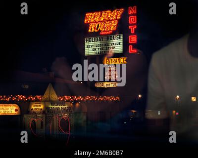 View from bus of neon lights and two hearts, neon sign for hotel and wedding chapel, Wedding Chapel at night, passengers reflected in window pane Stock Photo