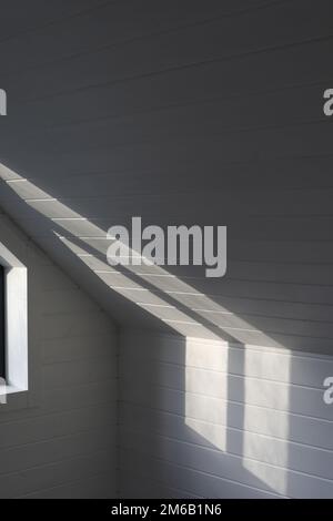 Sunlight on the white wooden wall background with shadows from the window. Texture and pattern Stock Photo