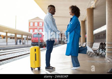 Romantic Black Couple Standing On Platform At Railway Station And Holding Hands Stock Photo