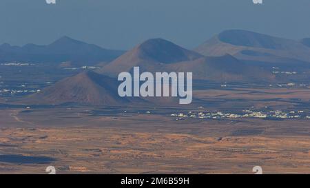 Ermita de las Nieves, hermitage, view to the south, red volcanic hill, volcanic cone, Timanfaya mountains, settlement with white houses, blue sea Stock Photo