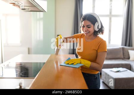 Smiling Young Arab Female In Wireless Headphones Making Cleaning At Home Stock Photo