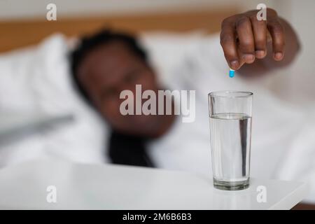 Fast Treatment. Sick Black Man Putting Medicine Pill Into Glass Of Water Stock Photo