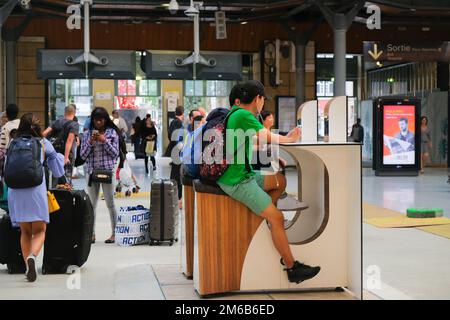 Paris, France - two young people cycle to charge their mobile phones for free inside Gare du Nord railway station. Innovative exercise motivation. Stock Photo