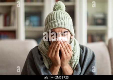 Unhappy arab man feeling bad, blowing his nose at home Stock Photo