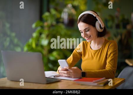 Cheerful young IT woman using headphones while working online Stock Photo
