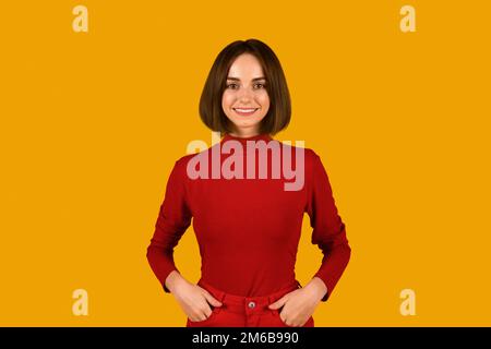 Cute young brunette woman posing on orange studio background Stock Photo