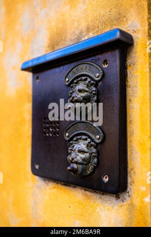 Close up of a venice doorbell in the shape of a lion's mouth on an orange wall during winter 2022 Stock Photo