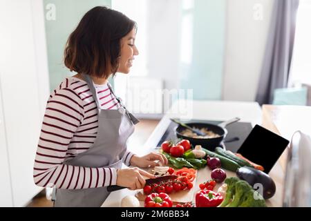 Young woman cooking at home, using digital tablet, mockup Stock Photo