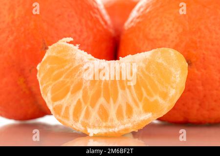 One slice and three whole sweet organic tangerines, macro, isolated on white background. Stock Photo
