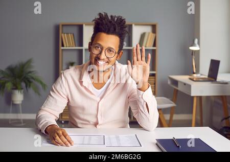 Portrait of an African American man waving hello at an online conference via a video call Stock Photo