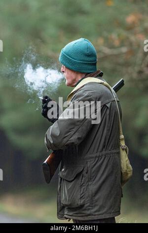 man smoking cigarette with shotgun Stock Photo