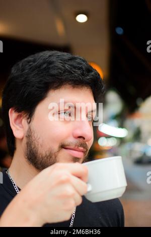 A caucasian, attractive man enjoying his morning coffee in the outdoor cafe, vertical Stock Photo