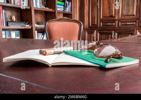 Set of Notebooks on Desk with Pencils and Glasses Stock Photo