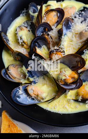 Freshly cooked mussles in wine and creamy sauce in a plate on a table Stock Photo