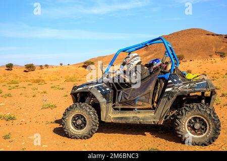 Merzouga, Morocco - Feb 26, 2016: Blue Polaris RZR 800 and pilots in Morocco desert near Merzouga. Merzouga is a small village l Stock Photo