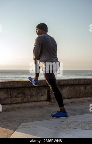 Man with beanie on head does stretch exercises Stock Photo