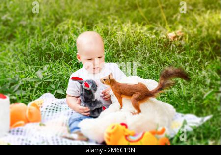 Little child spring in the park amazedly looks on insolent squirrel Stock Photo