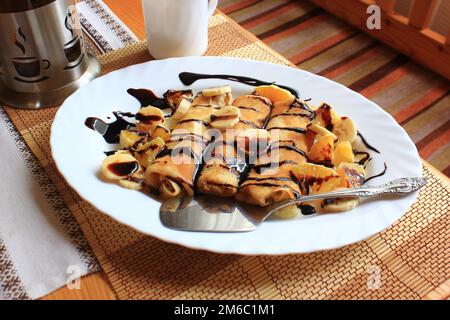 Pancakes stuffed with semolina, bananas and oranges drenched dark chocolate Stock Photo