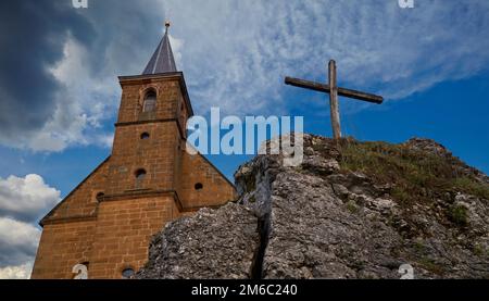 View on a church and a cross in front of a wonderful clouded sky Stock Photo