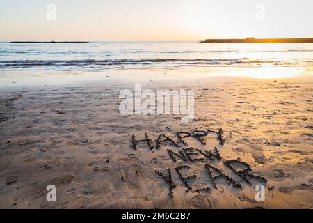 "Happy new year" written on the beach during sunset, photo with copy space Stock Photo