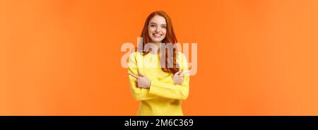 Choices, shopping, winter holidays concept. Cute smiling redhead girl with curly red hair, yellow sweater, pointing sideways, cross hands over chest Stock Photo