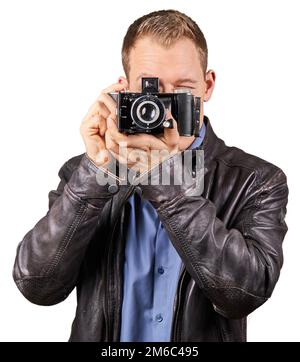 Young man with a leather jacket holding an old vintage camera and pointing at the camera - Isolated. Stock Photo