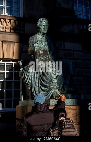A tourist rubs the toe on the statue of the Scottish Philosopher David Hume for good luck on Edinburgh's Royal Mile.