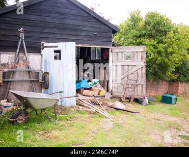 An open wooden shed in the countryside with tools and equipment on farm Stock Photo