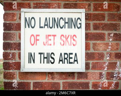 Old retro sign lettering on wall saying no launching of jet skies in this area Stock Photo