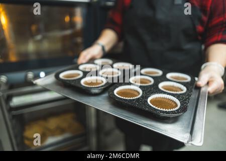 Unrecognizable pastry chef showing ready to bake chocolate muffins. Home made cupcakes baked in kitchen oven. High quality photo Stock Photo