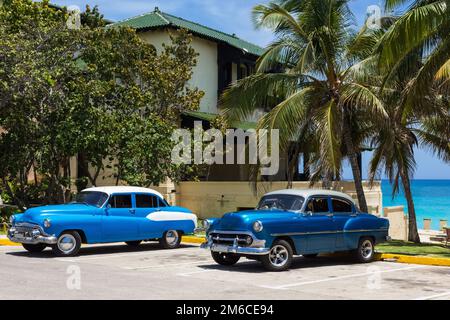 American blue classic cars with white rofo parked on the beach under palms in Varadero Cuba Stock Photo