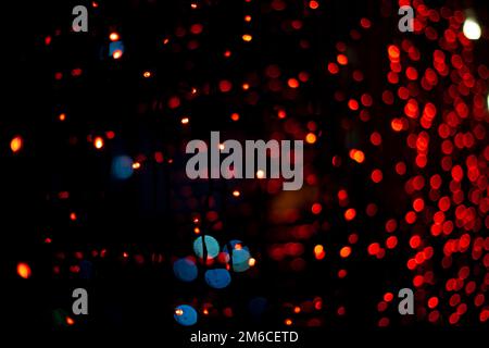 Red garlands on window. Lights in dark. Red lamps. Interior details. Stock Photo