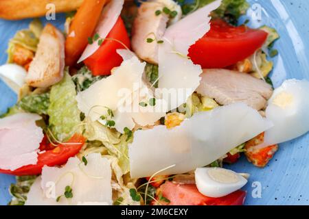 Fresh salad of chicken with vegetables and cheese, on a blue background Stock Photo
