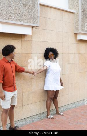 friends standing against a wall, talking, laughing and enjoying each other's company. Stock Photo