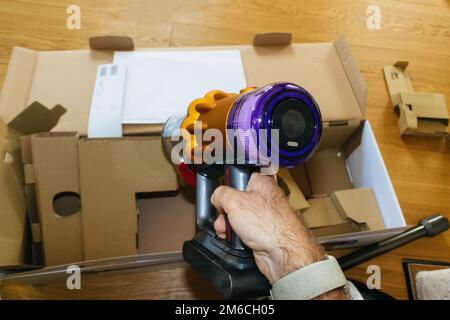 Paris, France - Jul 4, 2022: Man hand holding during unboxing new modern wireless Dyson V12 Detect Slim Absolute Vacuum Cleaner powerful cordless colorful cyclonic dust collection Stock Photo
