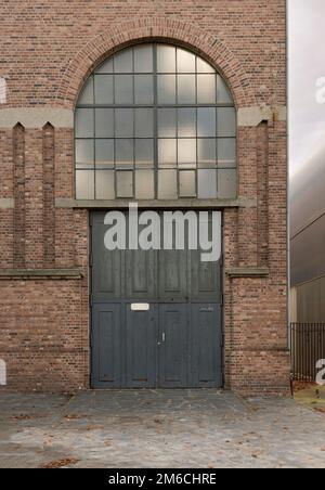 Genk. Limburg - Belgium 10-11-2020. Fragment of an old building with a gate and a stained-glass window. Late 19th early 20th century style Stock Photo