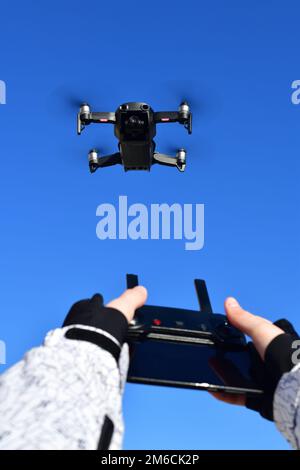 Quadrocopter flies in sky and hands with a control panel. Stock Photo