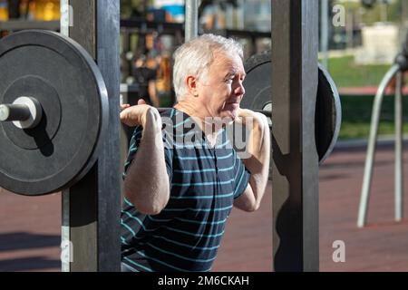 Elderly man lifting weights in Outdoors Gym Stock Photo